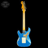 A blue electric guitar with a heavily distressed, worn finish and a natural wood neck, shown against a solid black background. A circular 'TONE SHOP' watermark is visible in the top-left corner.