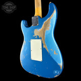 A blue electric guitar body with heavy distressed wear and bare wood showing through, photographed against a black background. A white plate is visible on the back, and part of a wooden neck is visible at the top.