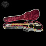 Guitar in a red-lined case with 'Tone Shop' logo in the corner.