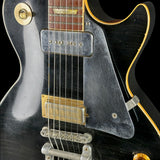 Close-up of a black electric guitar with gold hardware on a black background