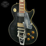 Black electric guitar with a clear case on a black background, featuring the 'Tone Shop' logo.