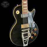 Black electric guitar with gold hardware on a black background, featuring the 'Tone Shop' logo.