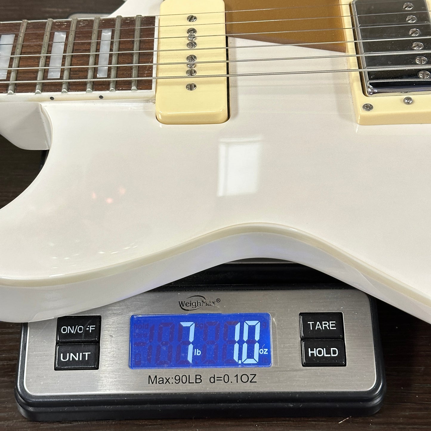 White electric guitar on a digital scale displaying weight