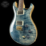 Blue electric guitar with a wavy finish on a black background, featuring the Tone Shop logo.