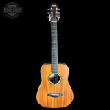 A Taylor acoustic guitar with a natural wood body and dark neck, shown against a solid black background with a Tone Shop watermark in the top-left corner.