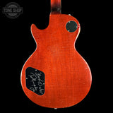 Back of a red electric guitar with a visible brand logo on a black background