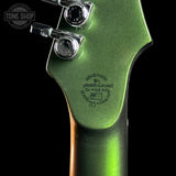Close-up of the back of a green electric guitar headstock with three chrome tuning pegs and engraved maker text reading 'Handmade by Omnix Guitars' on a black background.