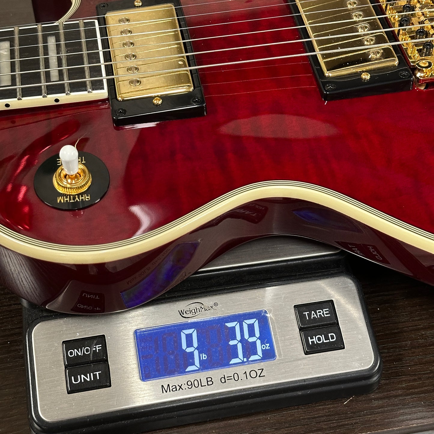 Red electric guitar on a digital scale displaying weight
