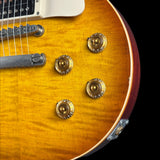 Close-up of a sunburst electric guitar with three gold knobs on a black background