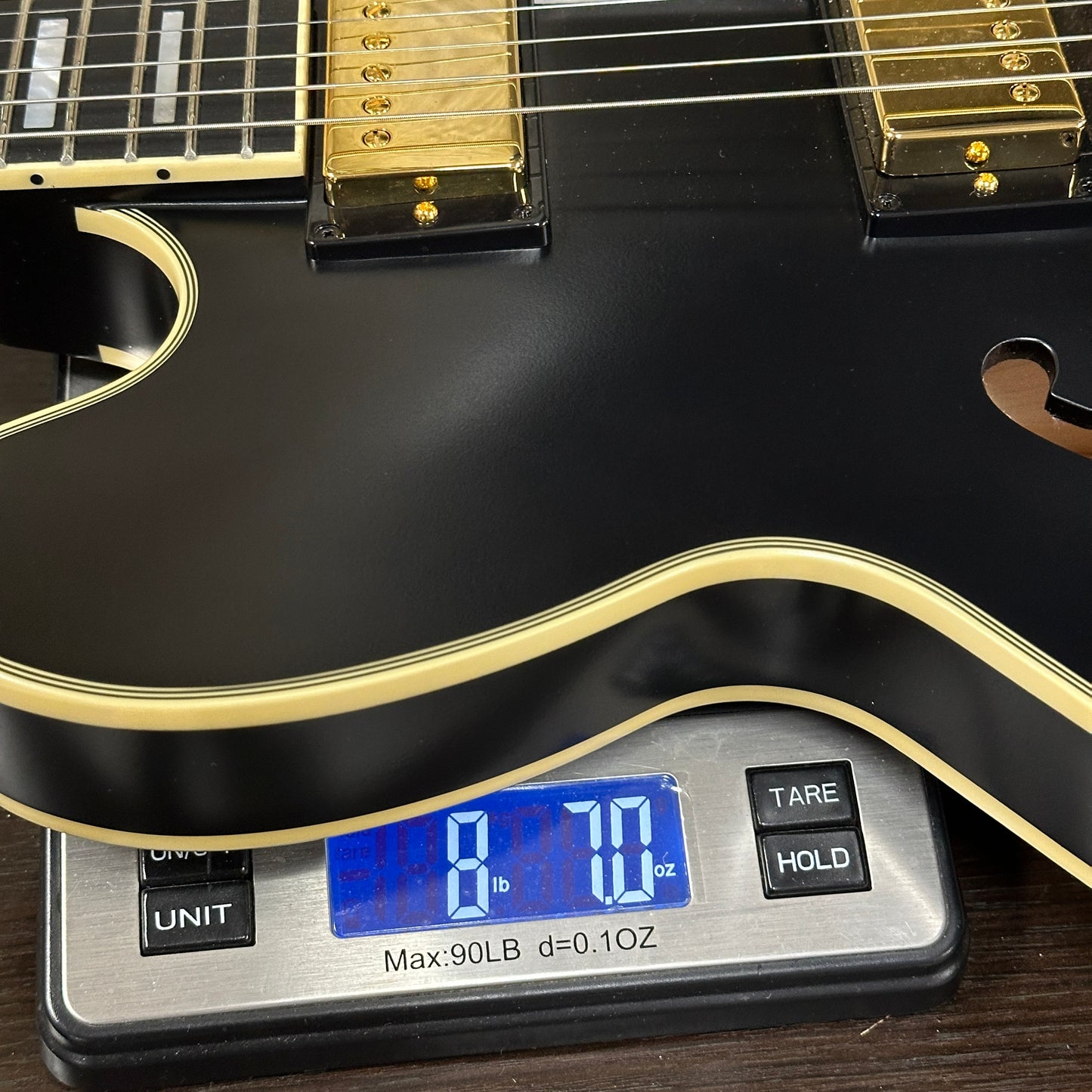 Black electric guitar on a digital scale displaying weight