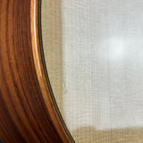 Close-up detail of a round wooden cabinet or mirror frame with a warm brown wood grain and a light beige textured fabric or glass backing.