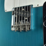 Close-up of a guitar bridge with 'Fender' branding on a blue guitar body.