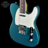 Blue electric guitar with a white pickguard on a black background, featuring the Tone Shop logo.