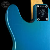 Close-up of a blue electric guitar with a visible brand logo on a black background.