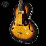A vintage-style electric guitar with a sunburst finish, featuring a dark brown pickguard, dual pickups, and a metal tailpiece, shown against a black background with a Tone Shop watermark in the top left corner.