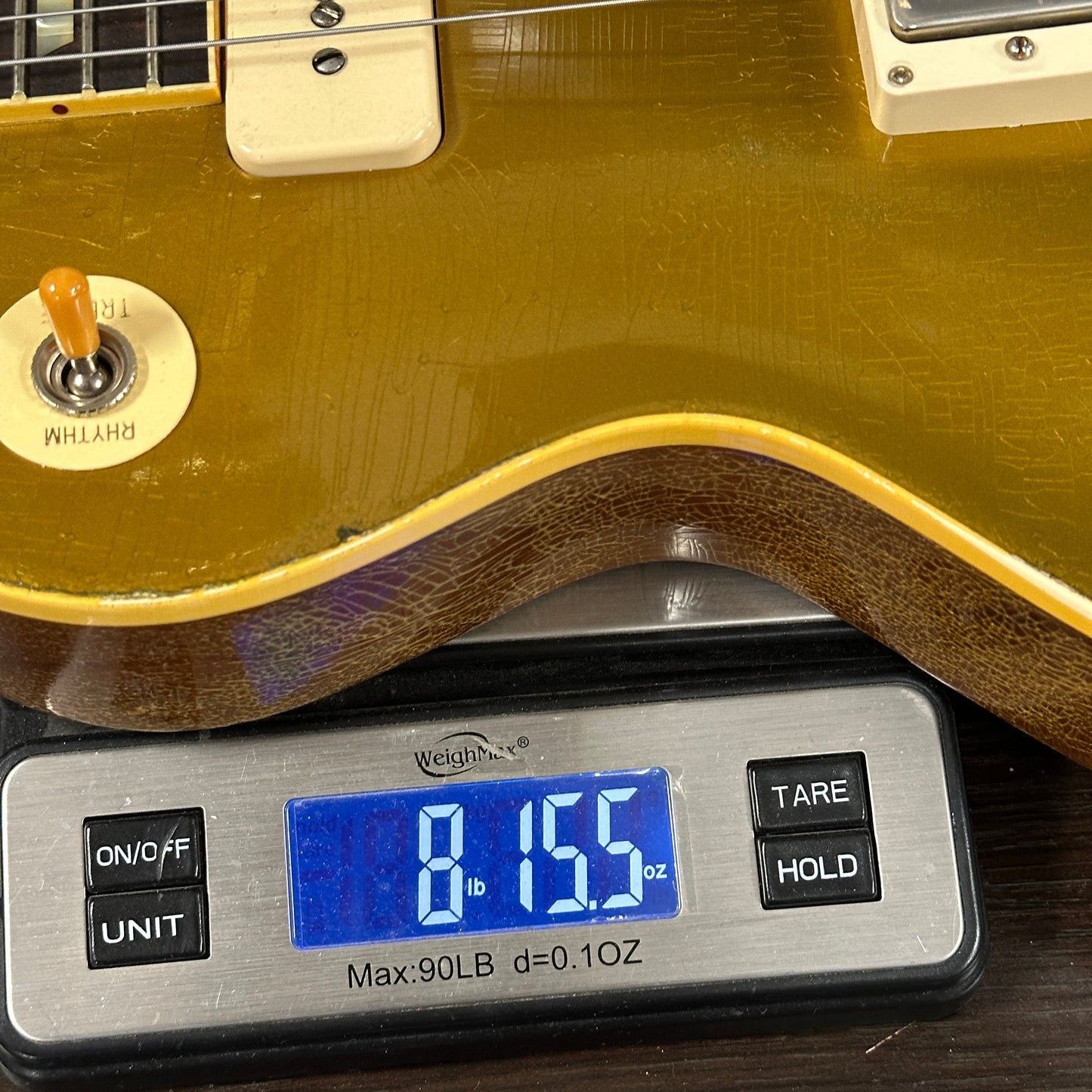 Guitar being weighed on a digital scale with a display showing weight.