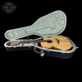 Acoustic guitar in an open hardshell case on a black background with 'Tone Shop' logo.