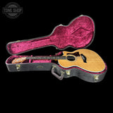 Acoustic guitar in a black case with pink interior on a black background, featuring 'Tone Shop' logo.