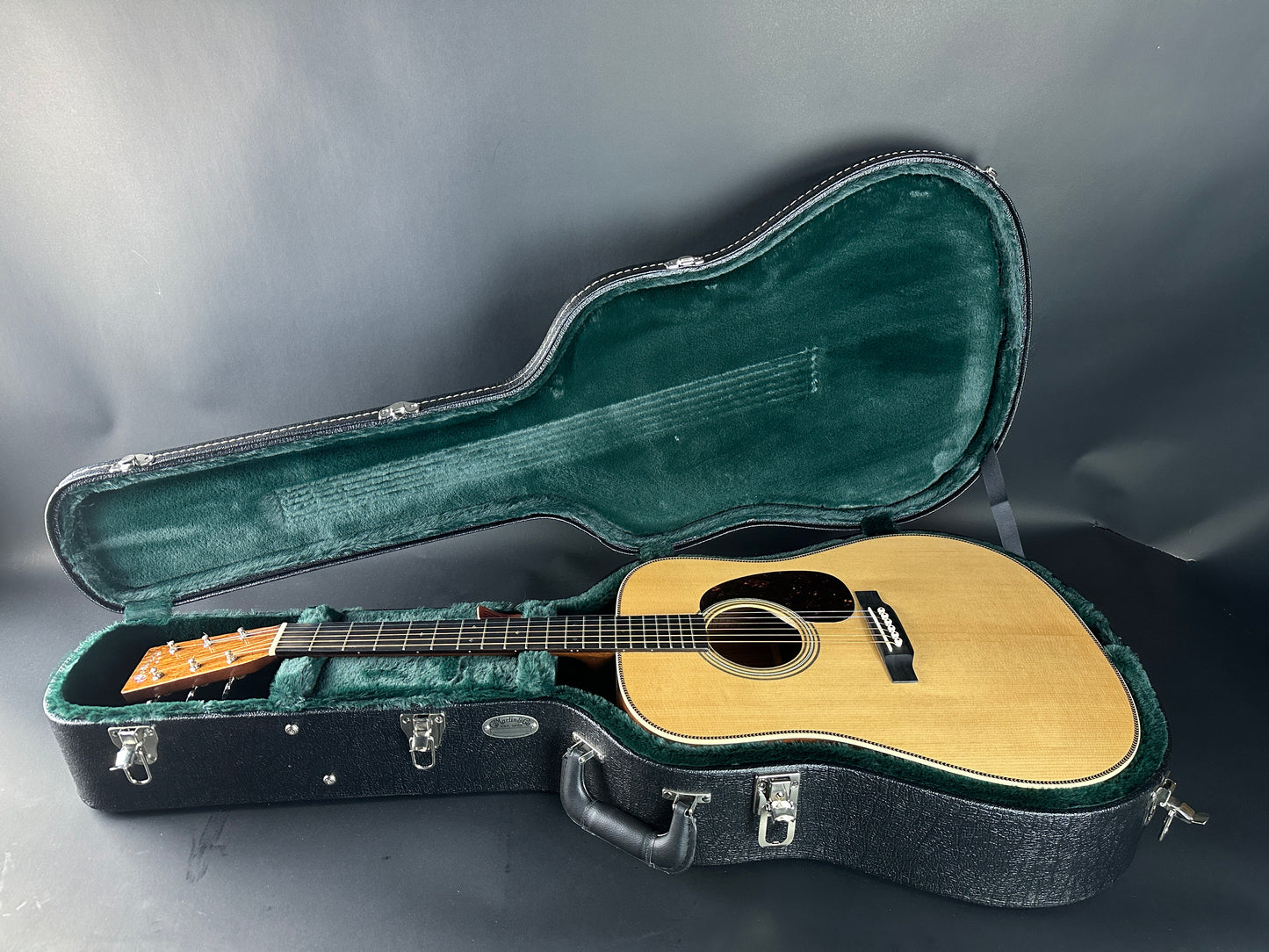 Acoustic guitar in an open case on a gray background
