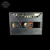 A black guitar amplifier cabinet with the front baffle removed to show the internal speaker and control panel, photographed against a solid black background. A Tone Shop watermark is visible in the top-left corner.