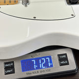 Close-up of a white guitar body resting on a digital scale displaying 7.127 lbs.