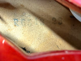 Close-up of the interior lining of a red bag or case, showing a tan/beige suede-like material with faint blue and dark gray stamped markings.