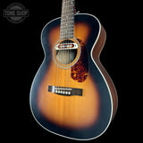 Acoustic guitar with a sunburst finish on a black background, featuring the Tone Shop logo.