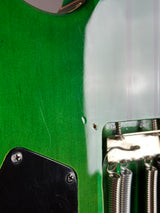 Close-up detail of a green electric guitar body showing the glossy finish, metal spring hardware, screws, and part of a black pickguard.