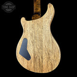 The back of an electric guitar showing a natural wood grain finish, a black pickguard, and part of a dark wood neck, set against a solid black background with a Tone Shop watermark in the top left.