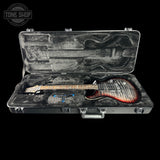 An electric guitar with a red and black flame finish sits inside an open hard case with a gray foam insert. The case is shown against a solid black background, with a Tone Shop watermark in the upper left corner.