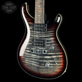 A double-cutaway electric guitar with a flamed maple top, featuring a dark brown and black sunburst finish with a glossy black pickguard and chrome hardware, shown against a solid black background.