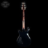 A black electric guitar shown from the back against a solid black background, with a visible Tone Shop watermark in the top-left corner.