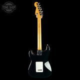 A black electric guitar shown from the back against a solid black background, featuring a natural maple neck and a white pickguard.