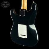 Rear view of a black electric guitar body with a white pickguard and maple neck, shown against a black background with a Tone Shop watermark in the top left corner.