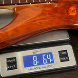 Wooden guitar neck on a digital scale displaying weight