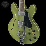 Green electric guitar with a black pickguard on a black background, featuring the Tone Shop logo.