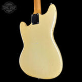 The back of a Fender Stratocaster electric guitar body in a cream or natural finish, showing the black pickguard and a portion of the natural wood neck, set against a solid black background.