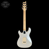 A white electric guitar shown from the back against a solid black background, featuring a natural wood neck and a gold-colored pickup cover.
