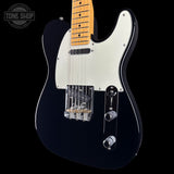 A black electric guitar with a white pickguard and maple neck, shown against a solid black background with a Tone Shop watermark in the top left corner.