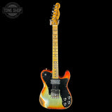 Electric guitar with a flame maple top and body on a black background, featuring the Tone Shop logo.