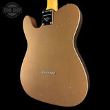 Back view of a gold electric guitar with 'Tone Shop' logo in the corner.