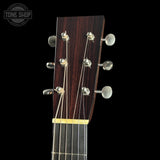 Close-up of a guitar headstock with tuning pegs on a black background, featuring the Tone Shop logo.