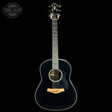 A black acoustic guitar with a glossy finish, featuring a light wood bridge and soundhole trim, shown against a solid black background. A Tone Shop watermark is visible in the top-left corner.