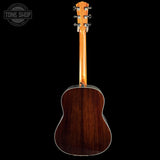 The back of a acoustic guitar with a glossy dark brown wood finish, shown against a solid black background with a Tone Shop watermark in the top left corner.