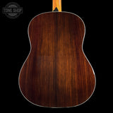 The back of an acoustic guitar made of rich, dark brown wood with a glossy finish, showing a white binding edge, set against a solid black background.
