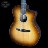 A cutaway acoustic guitar with a natural sunburst finish, shown from a front-three-quarter angle against a solid black background. A Tone Shop watermark is visible in the top-left corner.