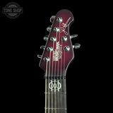 Close-up of the headstock of a six-string electric guitar against a black background. The headstock is glossy dark red with silver tuning pegs, white 'Troy Lee Designs' script and text, and a white 'MD' logo on the fretboard.