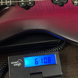 Close-up of a guitar body being weighed on a digital smart scale, with the scale display reading 6.108 kg.