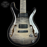 A close-up studio shot of an electric guitar body against a black background, showing a black-to-brown flame finish with a white pickguard and chrome hardware. A Tone Shop watermark is visible in the top-left corner.