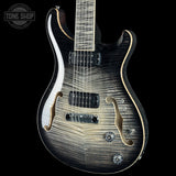 A double-cutaway electric guitar with a black and silver flame maple top, featuring gold-toned hardware and a black pickguard, shown against a solid black background.